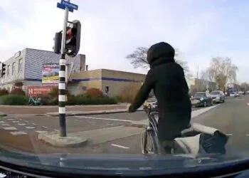 VIDEO: Fietster knalt met oortjes in door rood: betaalt de prijs met harde klap